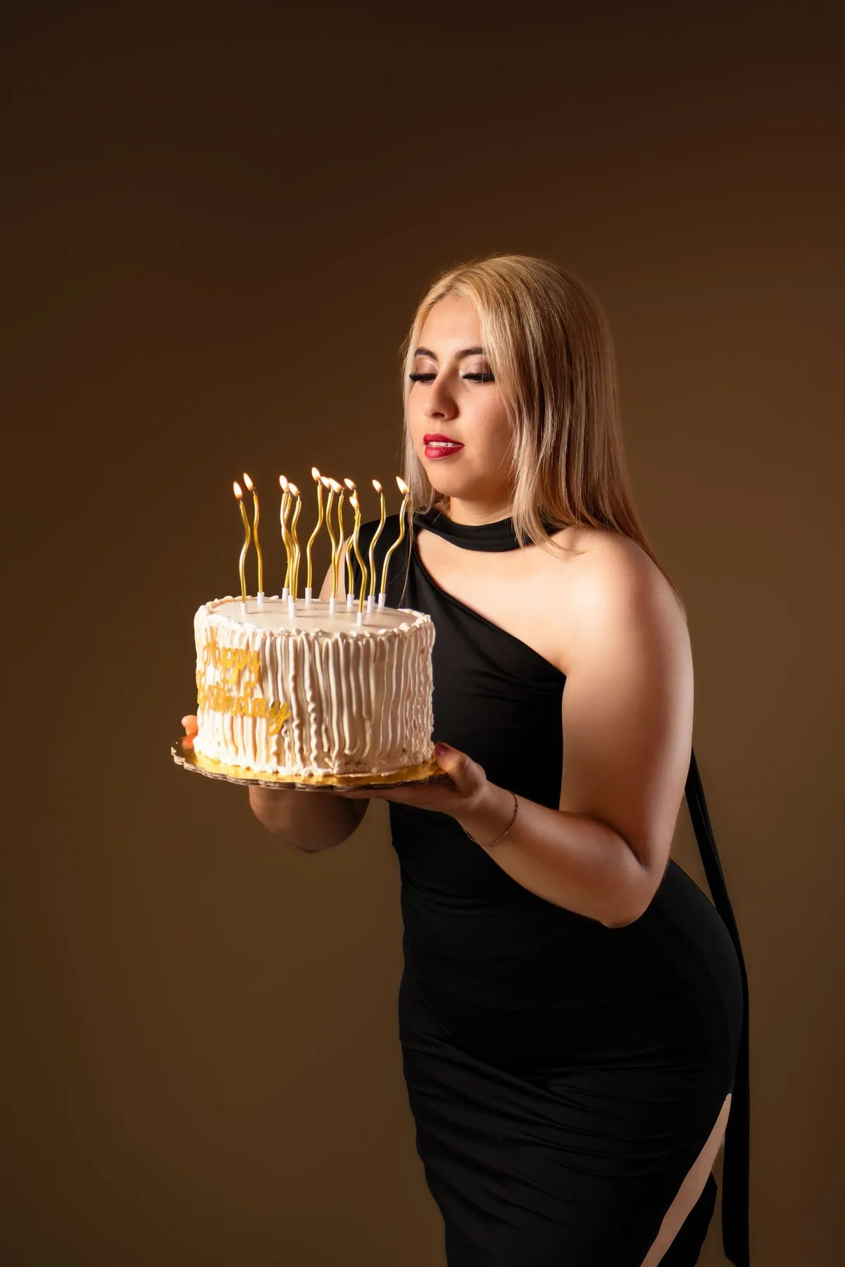 Natalia sostiene el pastel con velas doradas